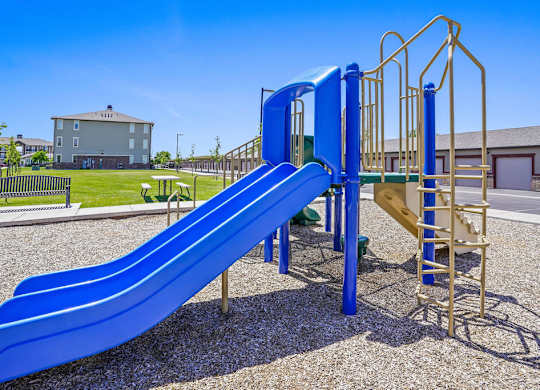 A blue slide in a playground with a yellow structure next to it.