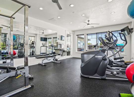 A spacious gym with a variety of equipment including a treadmill, weights, and a bench press.