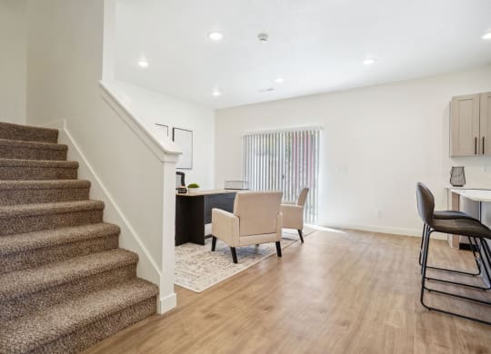 a living room with a staircase and a dining room with chairs