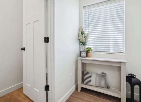 a hallway with a window and a table with a plant on it