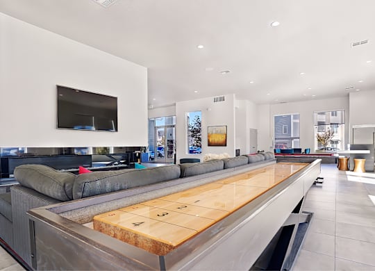 A modern living room with a long wooden table in the center.