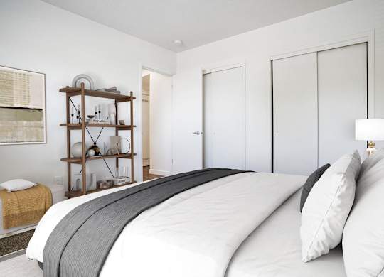 a white bedroom with a large bed and white closet doors