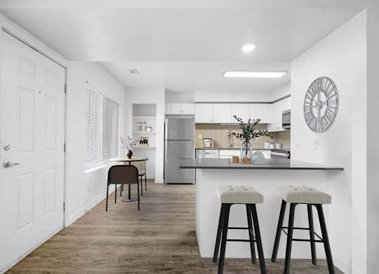 A kitchen with a bar stool and a clock on the wall.