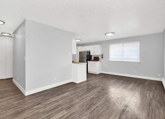 A spacious room with wooden flooring and white walls.