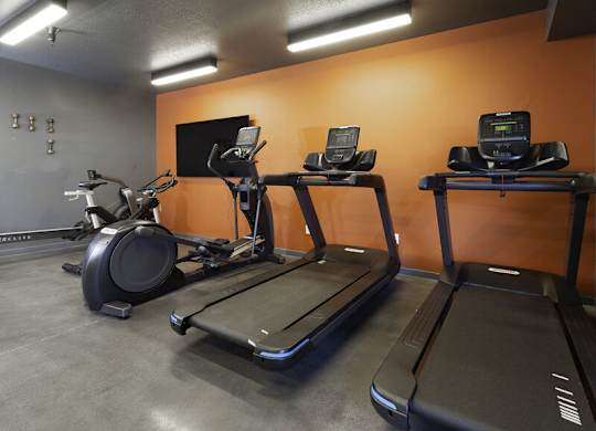 a gym with three treadmills and a tv