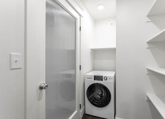 a small laundry room with a washing machine and a glass door