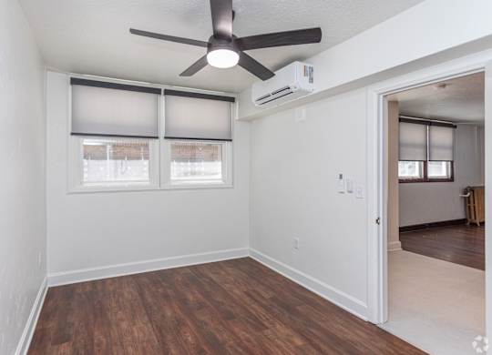 an empty living room with a ceiling fan and windows