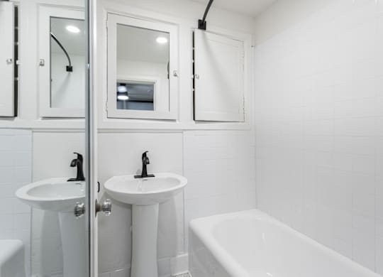 a white bathroom with two sinks and a tub and a shower