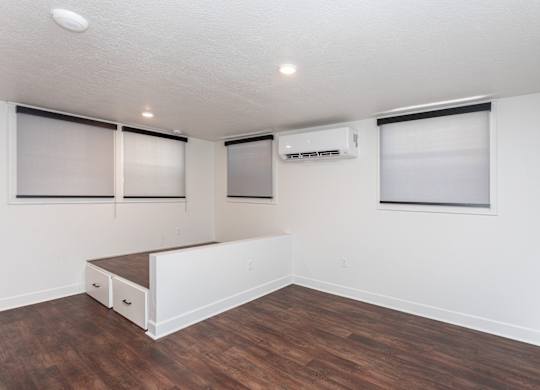 a living room with white walls and wood flooring and a window