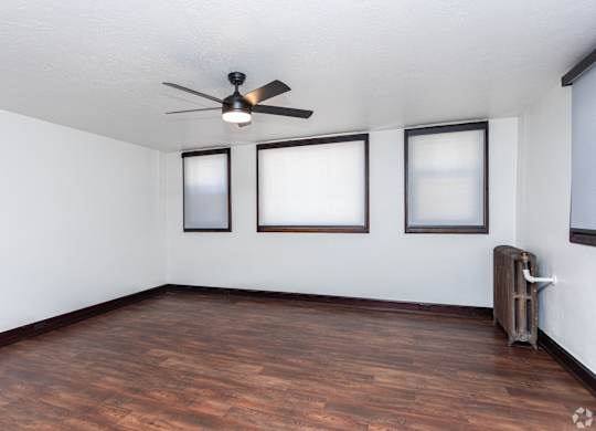 an empty living room with wood floors and a ceiling fan