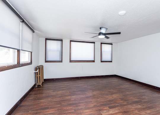 an empty living room with wood floors and a ceiling fan