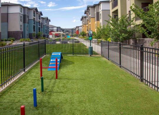 a grassy area with benches and a fence in front of an apartment complex