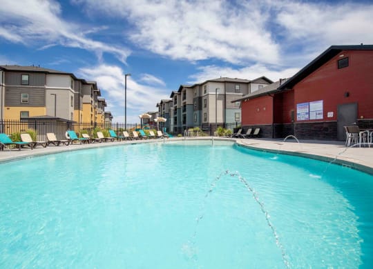 pool with lounge chairs and apartment buildings in the background