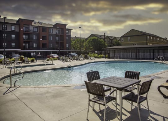 a swimming pool with a table and chairs and a building in the background