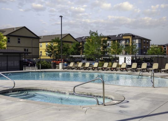 a swimming pool with chaise lounge chairs and buildings in the background