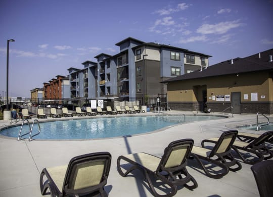 a swimming pool with chaise lounge chairs and a building in the background