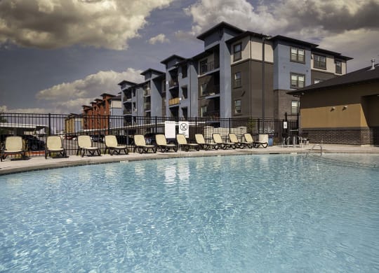 a swimming pool with chaise lounge chairs and a building in the background