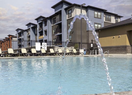a large pool with a fountain in front of a building