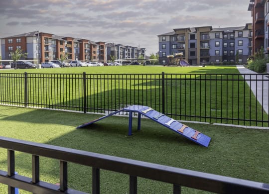 a blue slide sits in the middle of a grassy area in front of an apartment complex