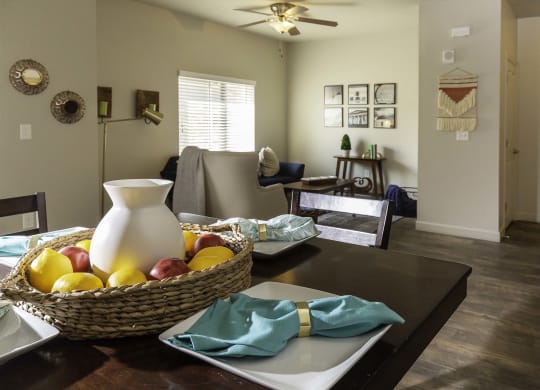 an open concept living room and dining room with a table with a pitcher and fruit on it