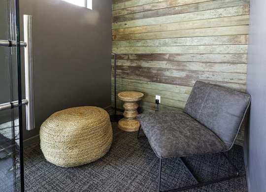 A grey chair sits in front of a wooden wall.