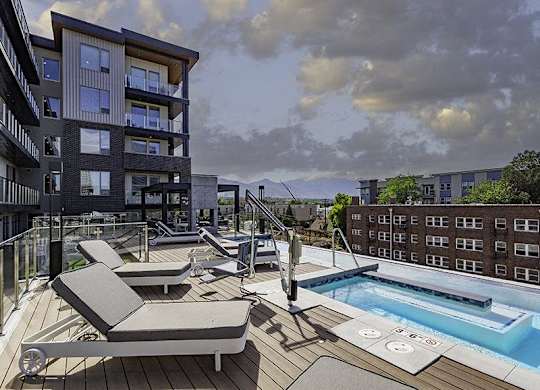 A modern apartment complex with a pool and sun loungers.