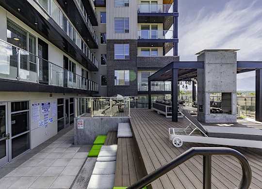 A modern building with a wooden deck and glass railings.