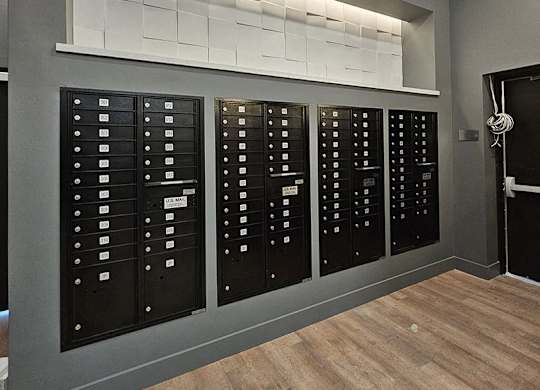 A wall of black mailboxes with white labels on them.