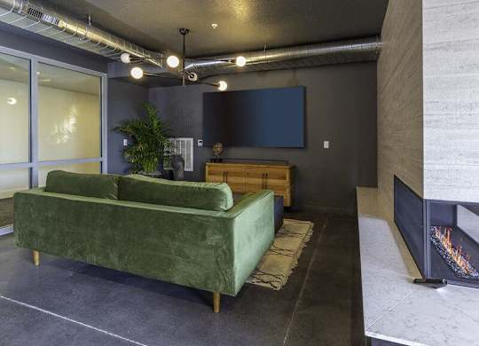 A living room with a green couch and a fireplace.