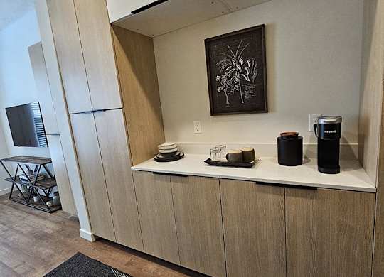 A kitchen area with a wooden cabinet and a framed picture on the wall.