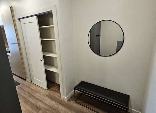 A white closet with a mirror and a bench.