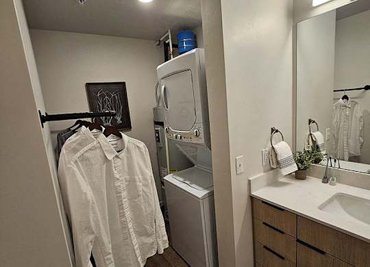 A white shirt hanging on a rack in a bathroom.