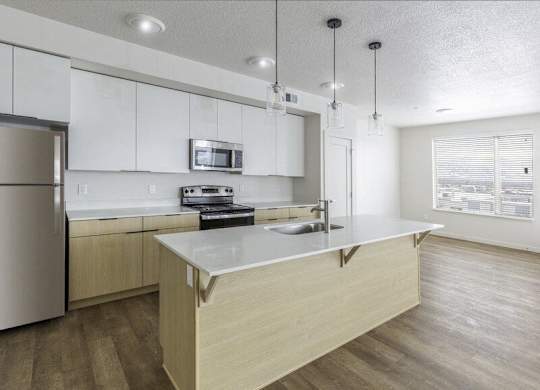 A kitchen with a refrigerator, microwave, oven, and sink.