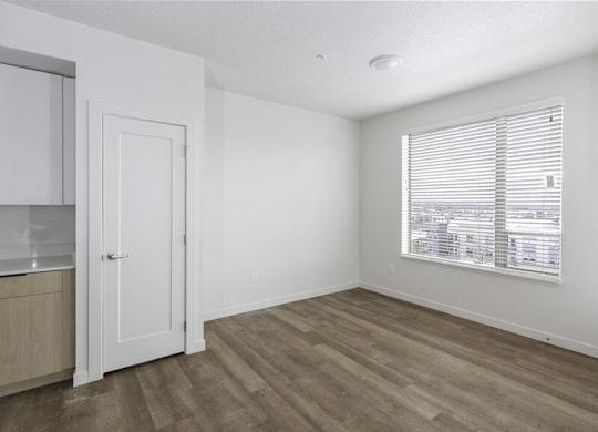 A room with a wooden floor and a window with blinds.