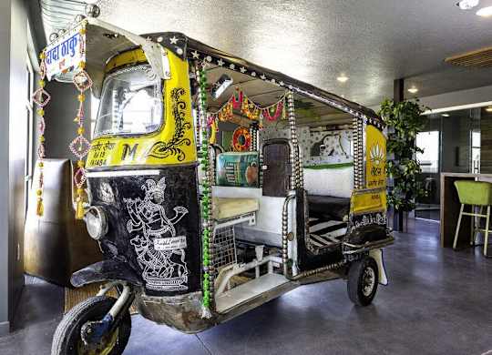A decorated auto rickshaw is parked inside a building.