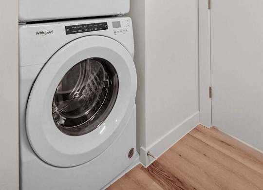 Two white Whirlpool washing machines stacked on top of each other.