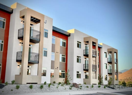 a row of modern apartments with balconies and a desert background