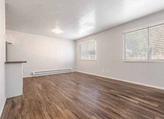 A room with wooden flooring and a window with blinds.