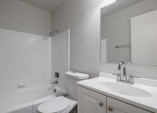 A white bathroom with a toilet, sink, and bathtub.