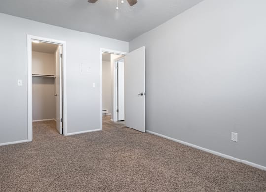 A room with carpeted floor and two open doors.