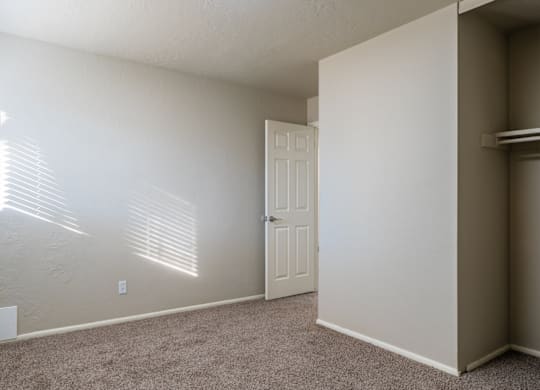 A room with a door and a window with blinds.
