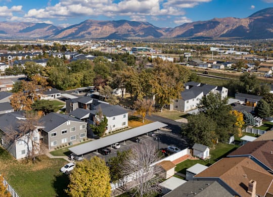 A suburban neighborhood with houses and trees in the foreground and mountains in the background.
