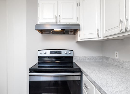 A black stove top oven with a silver range hood above it.