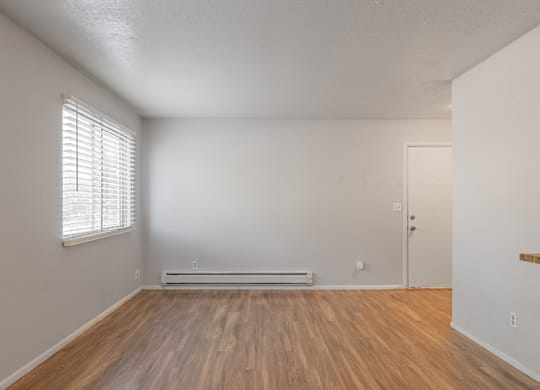 A room with wooden floors and a window with blinds.