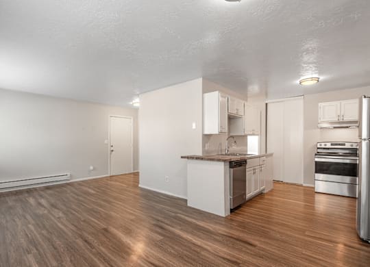A spacious kitchen with white cabinets and a wooden floor.