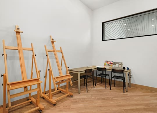 Two wooden easels stand in front of a white wall.