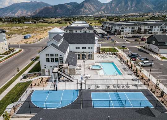 A large building with a pool and tennis court in front.