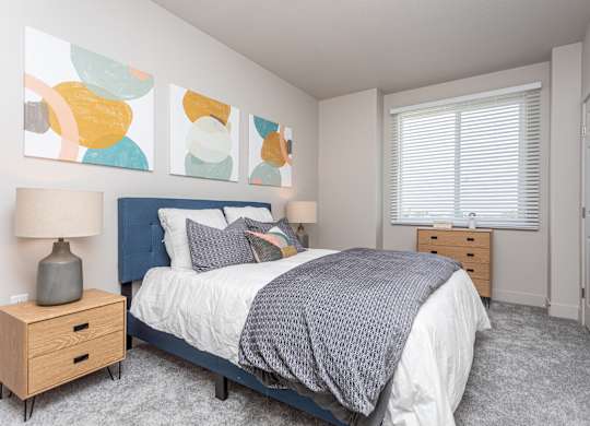 A bedroom with a bed, nightstand, and a painting on the wall.