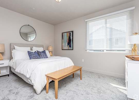 A bedroom with a large bed, a round mirror, and a painting on the wall.