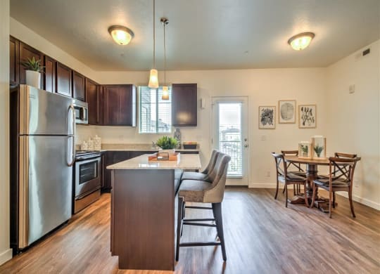 a kitchen with a large island and a stainless steel refrigerator at Aderra apartments for rent in Roy, Utah